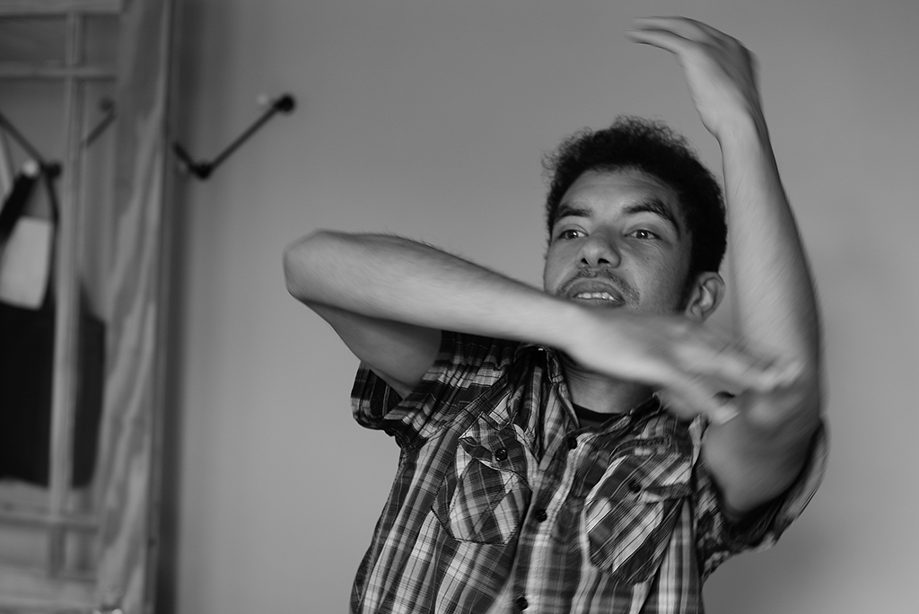 Black and white photo of DJ dancing with one arm stretched up and the other across his face