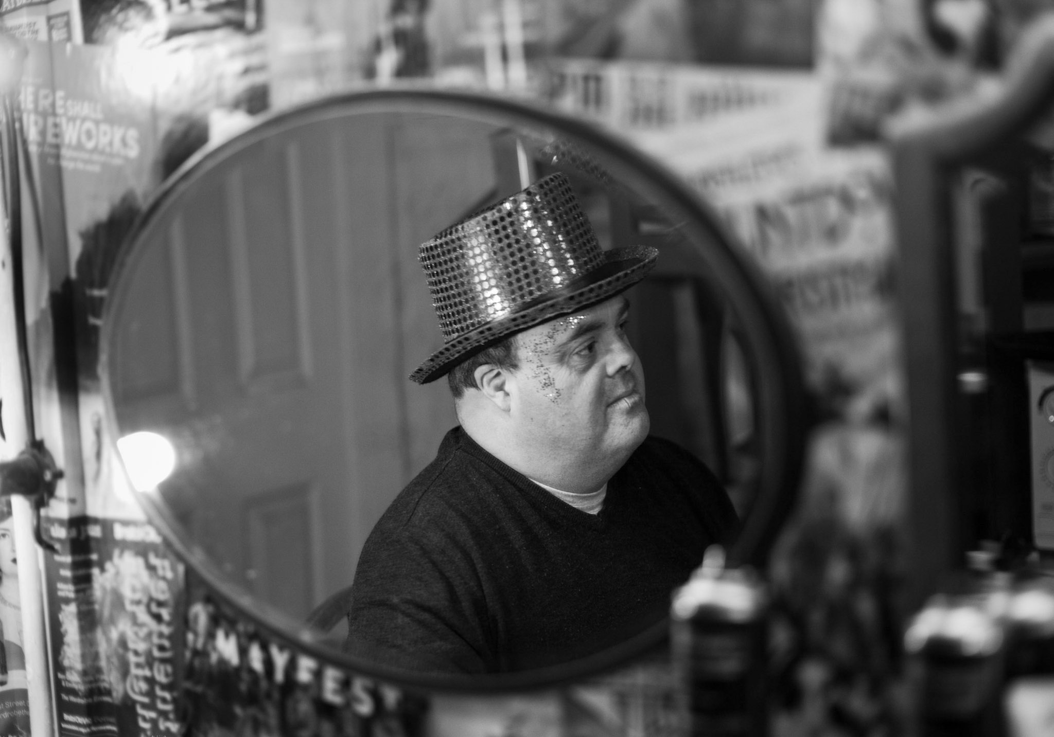 Black and white photo of Graham in front of a mirror with a sequined top hat on