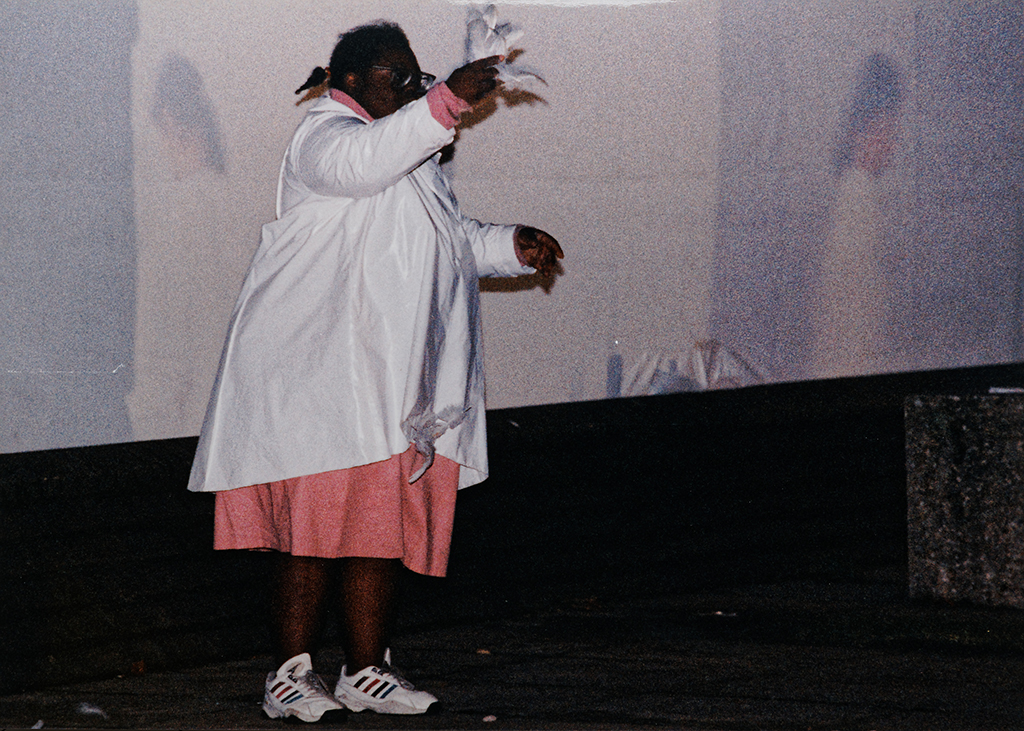 Photo of Natalie dancing outside with feathers in front of projection